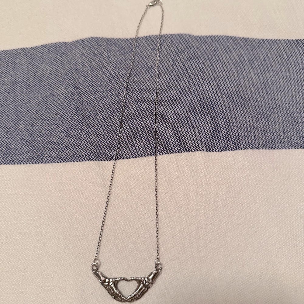 .925 sterling silver skeleton heart hands necklace.